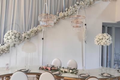 Miniature Le Grand Salon Salle de réception décorée avec des fleurs blanches, des tables élégantes et un éclairage rose tamisé.