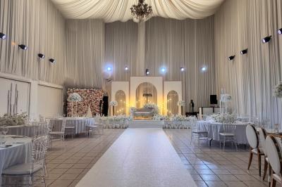 Miniature Le Grand Salon Salle de réception décorée avec des fleurs blanches, des tables élégantes et un éclairage rose tamisé.