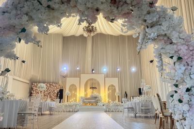 Miniature Le Grand Salon Salle de réception décorée avec des fleurs blanches, des tables élégantes et un éclairage rose tamisé.