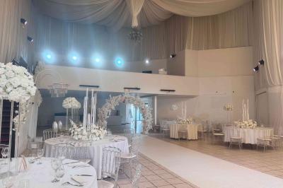 Miniature Le Grand Salon Salle de réception décorée avec des fleurs blanches, des tables élégantes et un éclairage rose tamisé.