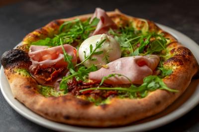 Miniature Location salle Lille (Nord) - Marta Bar Restaurant #9 Préparation d'une pizza avec des mains ajoutant des tranches de chorizo sur une pâte garnie de sauce tomate et fromage râpé.