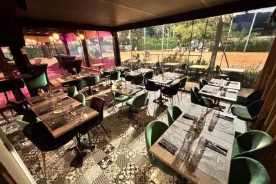 Miniature Location salle Le Bouscat (Gironde) - Côté Court #13 Entrée d'un café avec une grande terrasse, un parasol orange et des meubles en osier sous un ciel bleu.