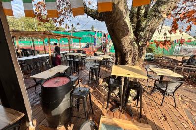 Miniature Location salle Le Bouscat (Gironde) - Côté Court #15 Entrée d'un café avec une grande terrasse, un parasol orange et des meubles en osier sous un ciel bleu.