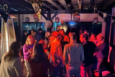 Miniature Location salle Le Bouscat (Gironde) - Côté Court #18 Entrée d'un café avec une grande terrasse, un parasol orange et des meubles en osier sous un ciel bleu.