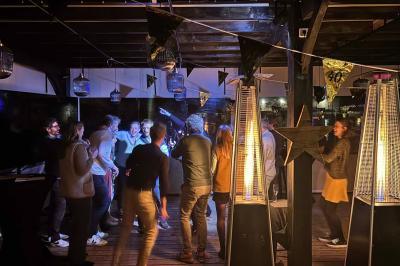 Miniature Location salle Le Bouscat (Gironde) - Côté Court #6 Entrée d'un café avec une grande terrasse, un parasol orange et des meubles en osier sous un ciel bleu.