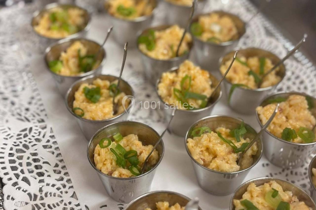 Petits ramequins en métal contenant du risotto crémeux garni de ciboulette, disposés sur un napperon blanc.