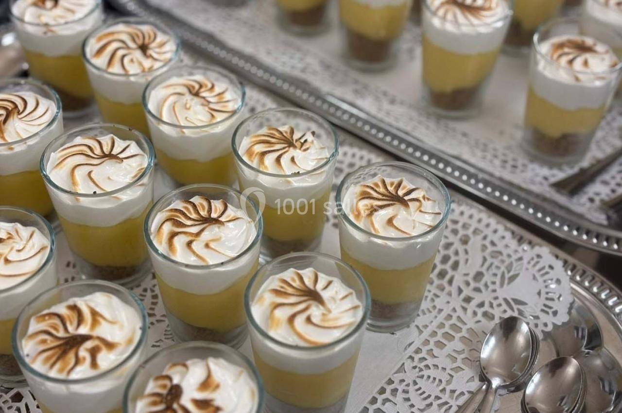 Verrines de dessert au citron avec meringue dorée, disposées sur un plateau argenté avec des cuillères à côté.
