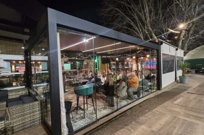 Miniature Location salle Le Bouscat (Gironde) - Côté Court #37 Entrée d'un café avec une grande terrasse, un parasol orange et des meubles en osier sous un ciel bleu.