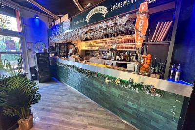 Miniature Location salle Le Bouscat (Gironde) - Côté Court #25 Entrée d'un café avec une grande terrasse, un parasol orange et des meubles en osier sous un ciel bleu.