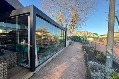 Miniature Location salle Le Bouscat (Gironde) - Côté Court #38 Entrée d'un café avec une grande terrasse, un parasol orange et des meubles en osier sous un ciel bleu.