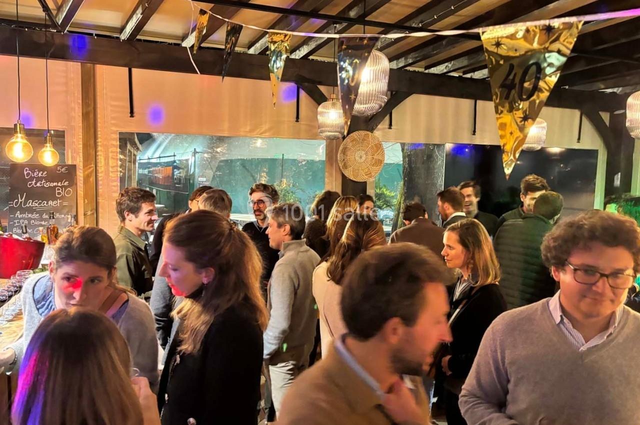 Groupe de personnes discutant lors d'une soirée conviviale dans un espace décoré avec des guirlandes et des lumières.
