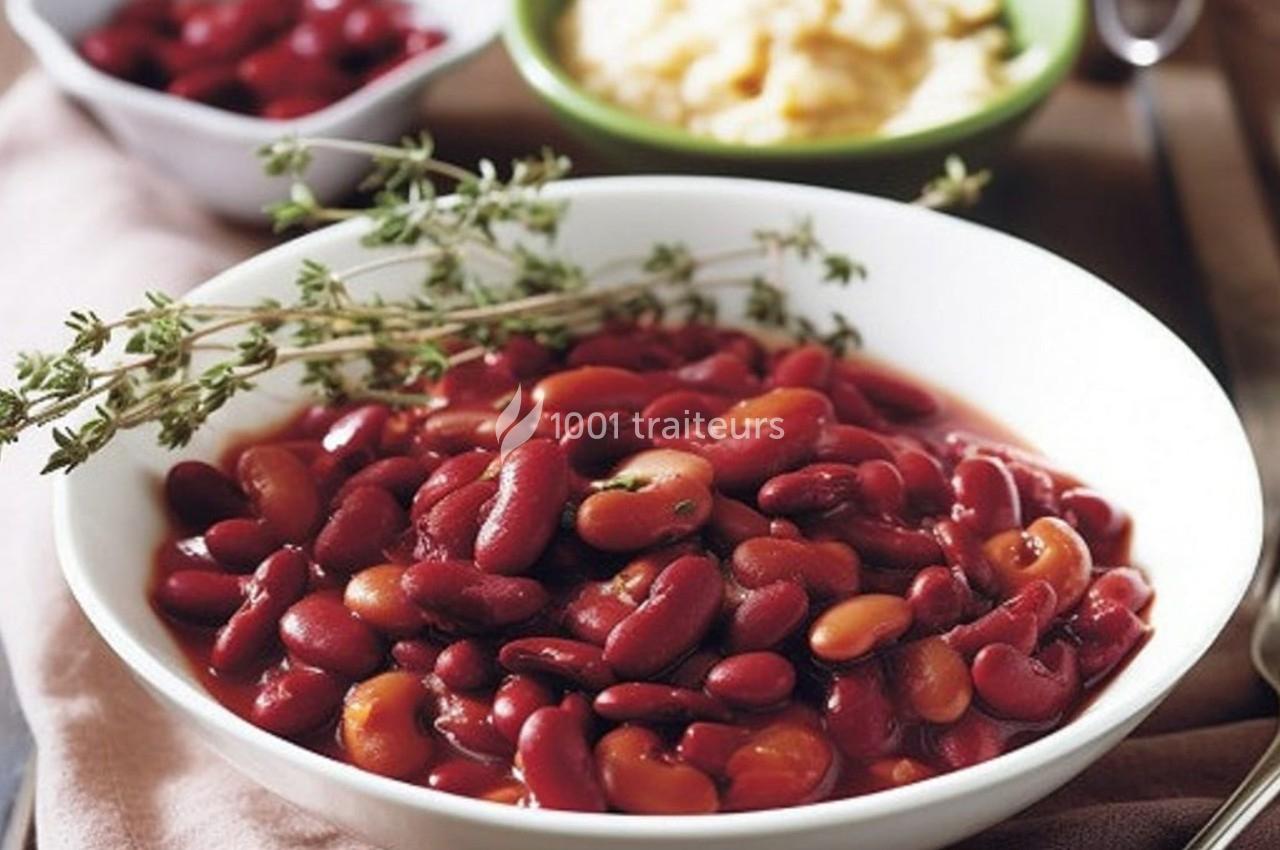 Bol de haricots rouges cuits garnis de branches de thym, avec des plats en arrière-plan.