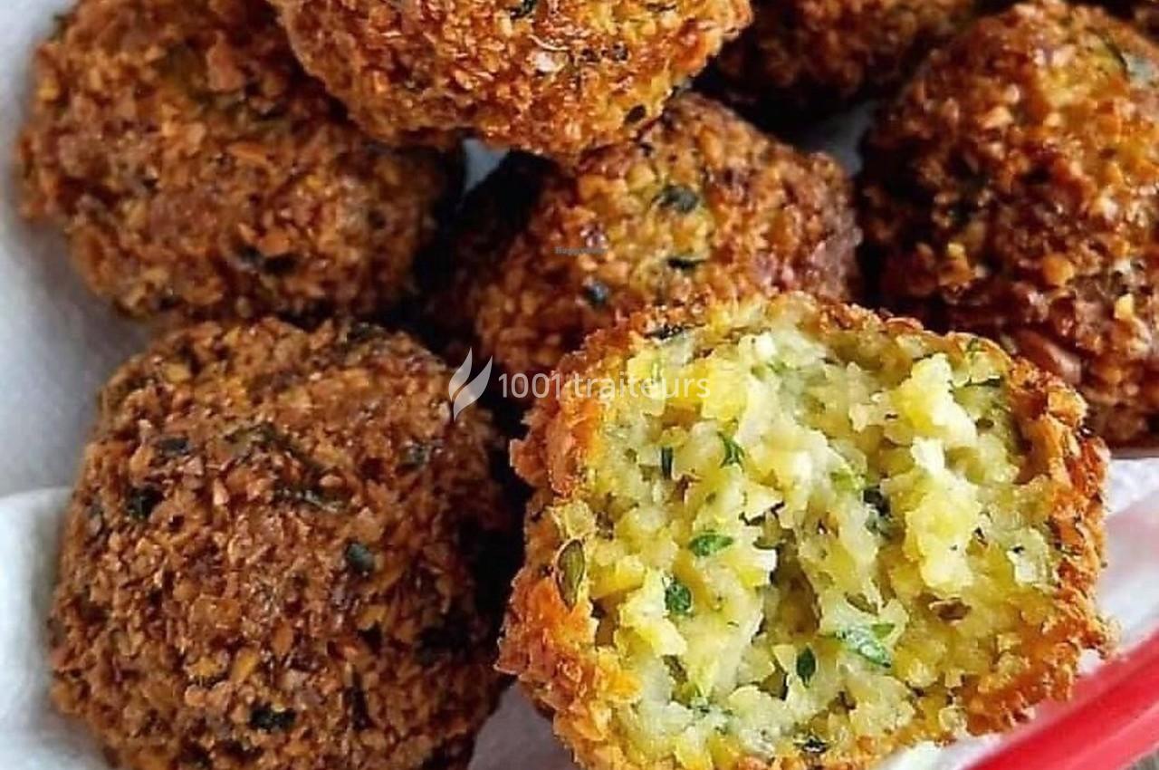 Boulettes de falafel dorées, dont une coupée en deux révélant une texture moelleuse et des herbes à l'intérieur.