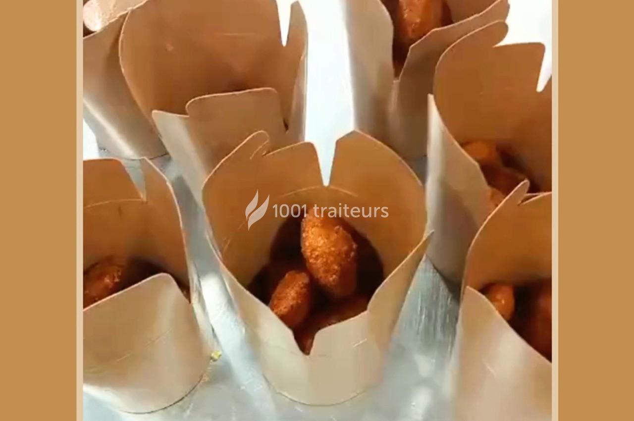 Croquettes dorées servies dans des contenants en carton brun disposés sur une surface métallique.