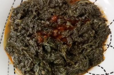 Miniature Traiteur Colmar (Haut-Rhin) - Afghane Kitchen #27 Plat de feuilles de légumes mijotées dans une sauce épicée, présenté dans une assiette blanche.