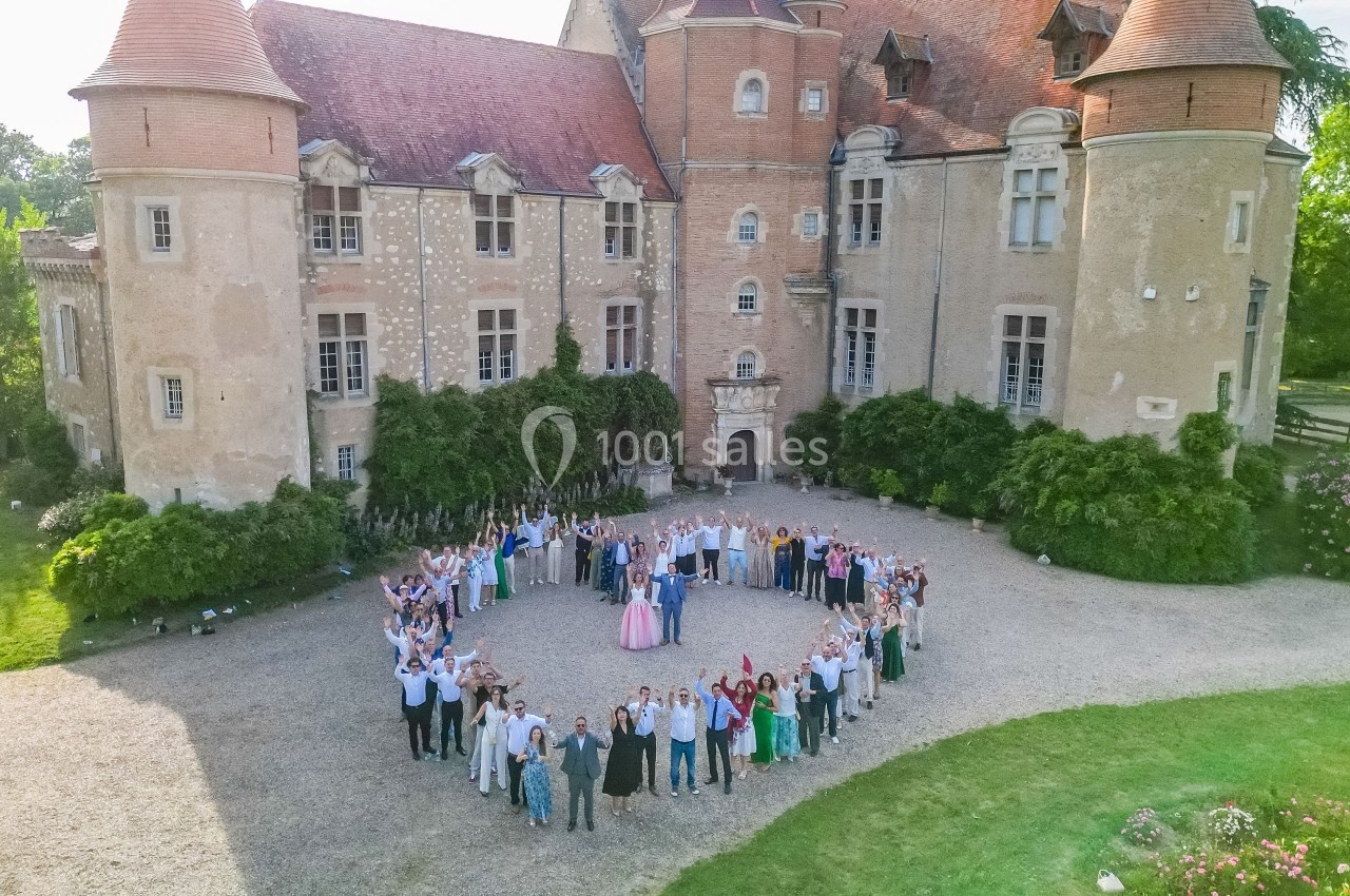 Groupe de personnes formant un cercle dans la cour d'un château avec des tours et des murs en pierre.