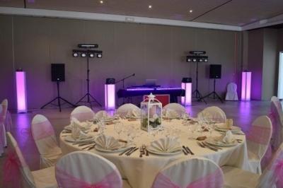 Deux enceintes sur trépieds et un caisson de basses posés sur un sol pavé devant une porte de garage.