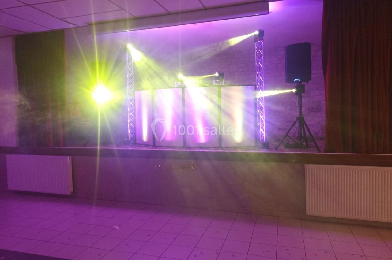 Installation de matériel de sonorisation et éclairage avec projecteurs colorés sur une scène dans une salle.