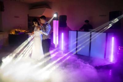 Deux enceintes sur trépieds et un caisson de basses posés sur un sol pavé devant une porte de garage.