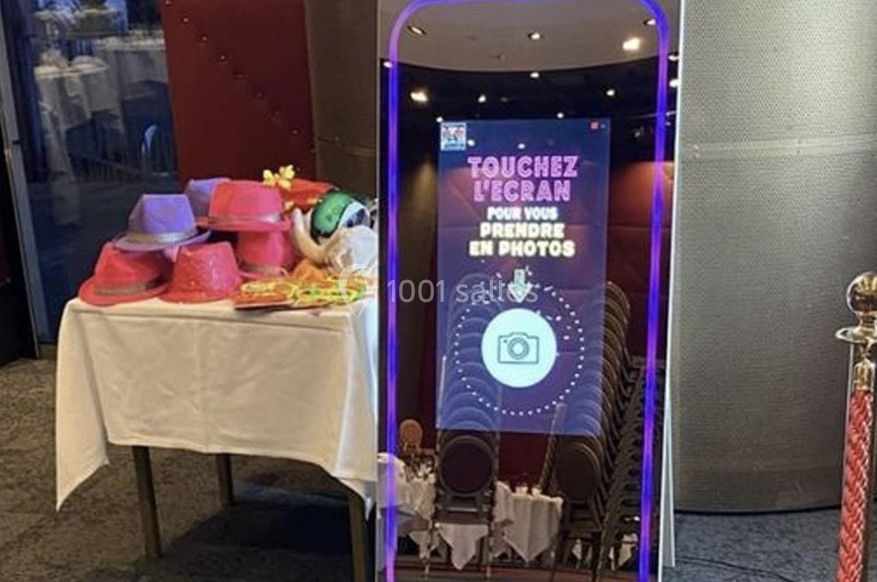 Miroir interactif pour prise de photos, entouré d'accessoires colorés sur une table à gauche.