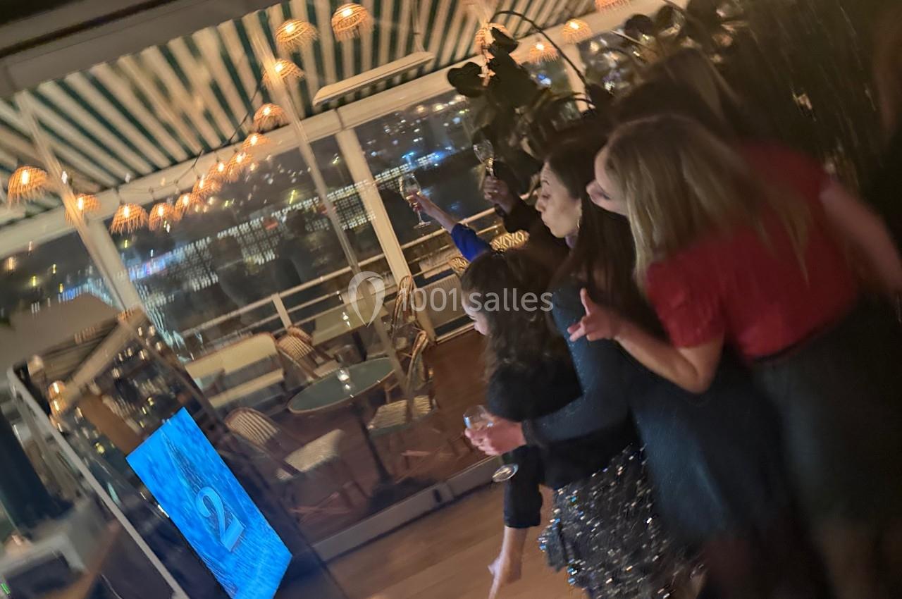 Des personnes rassemblées devant un écran interactif dans un espace lumineux avec vue nocturne sur l'extérieur.