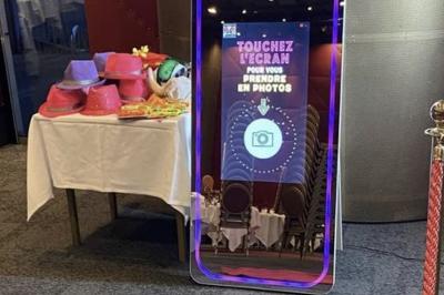 Deux personnes déguisées posent devant un smartphone affichant leur photo, accompagnées de deux autres en arrière-plan.