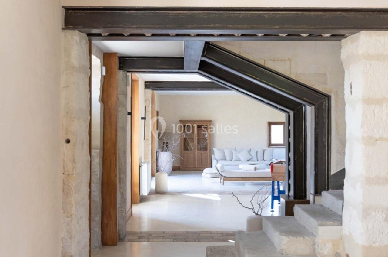 Vue d'un intérieur lumineux avec des poutres métalliques apparentes, un canapé et une armoire en bois au fond.