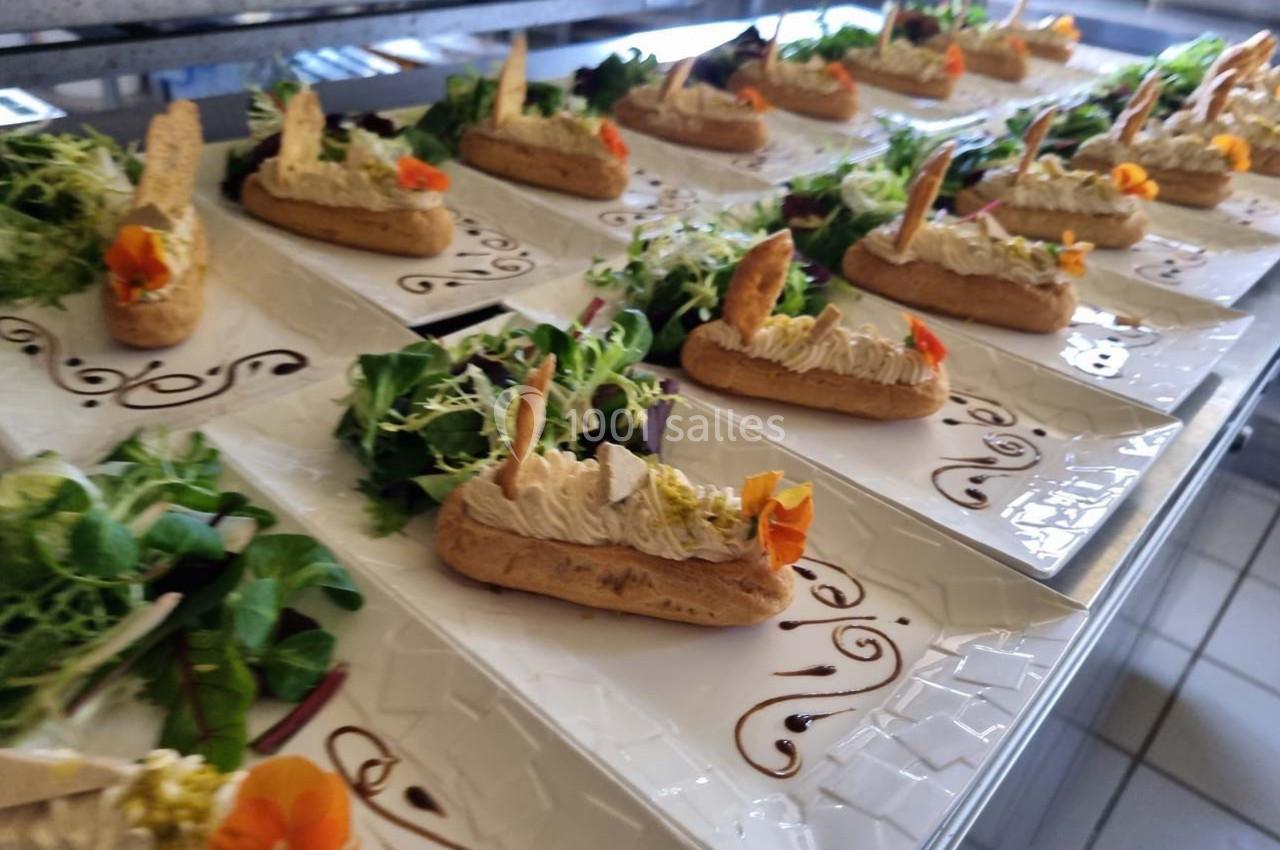 Assiettes dressées avec éclairs salés garnis de mousse, accompagnés de salade verte et décorés de fleurs comestibles.