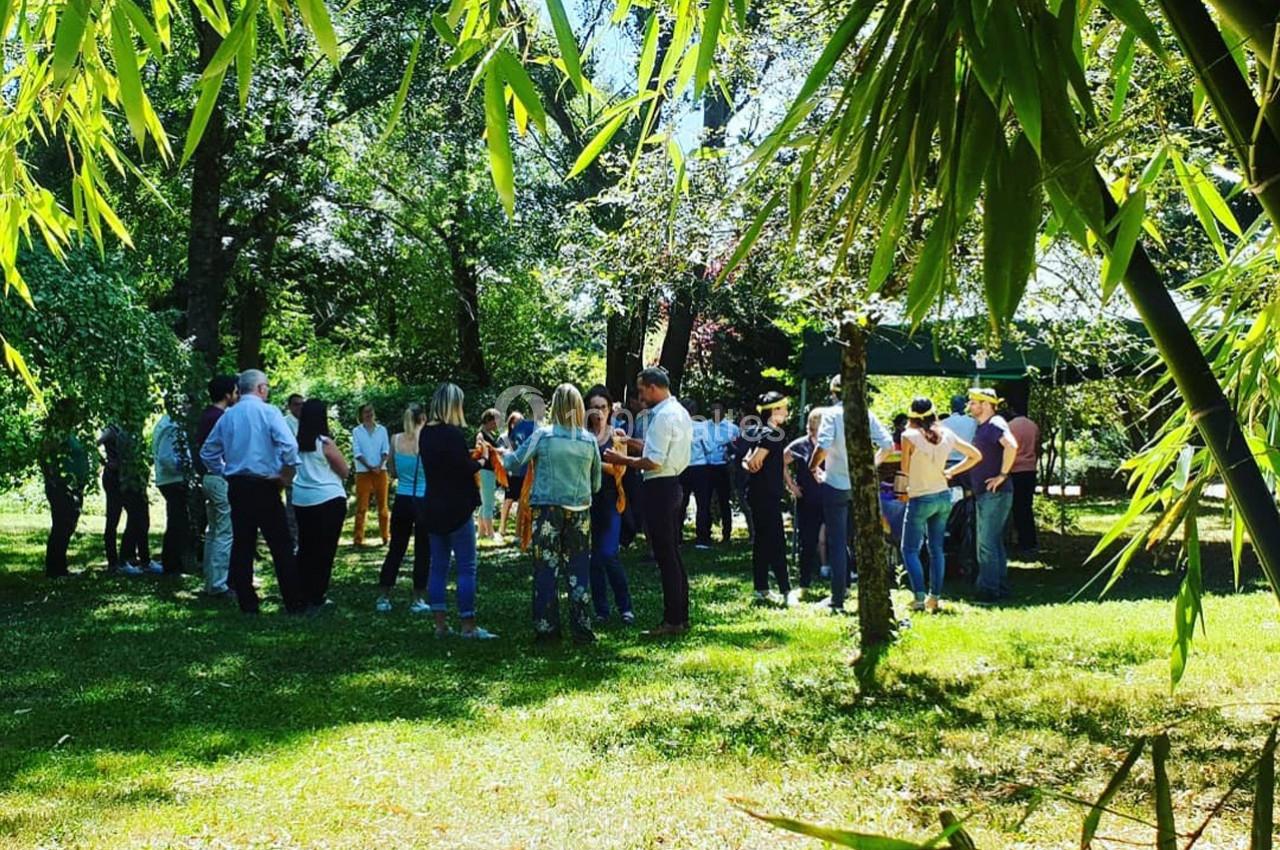 Un groupe de personnes échange dans un parc verdoyant, entouré d'arbres et de bambous, par une journée ensoleillée.
