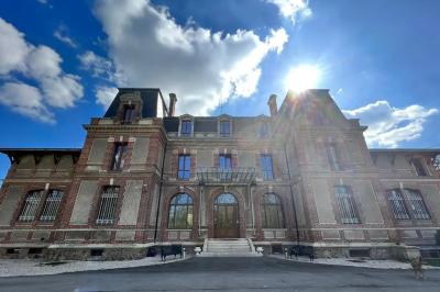 Centre de table floral avec roses roses, fleurs violettes et blanches, entouré de bougies et de verres sur une nappe blanche.
