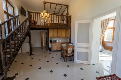 Chambre lumineuse avec lit double, meubles en bois sculpté, tapis décoratif et grande fenêtre avec rideaux.