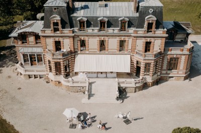 Chambre lumineuse avec lit double, meubles en bois sculpté, tapis décoratif et grande fenêtre avec rideaux.
