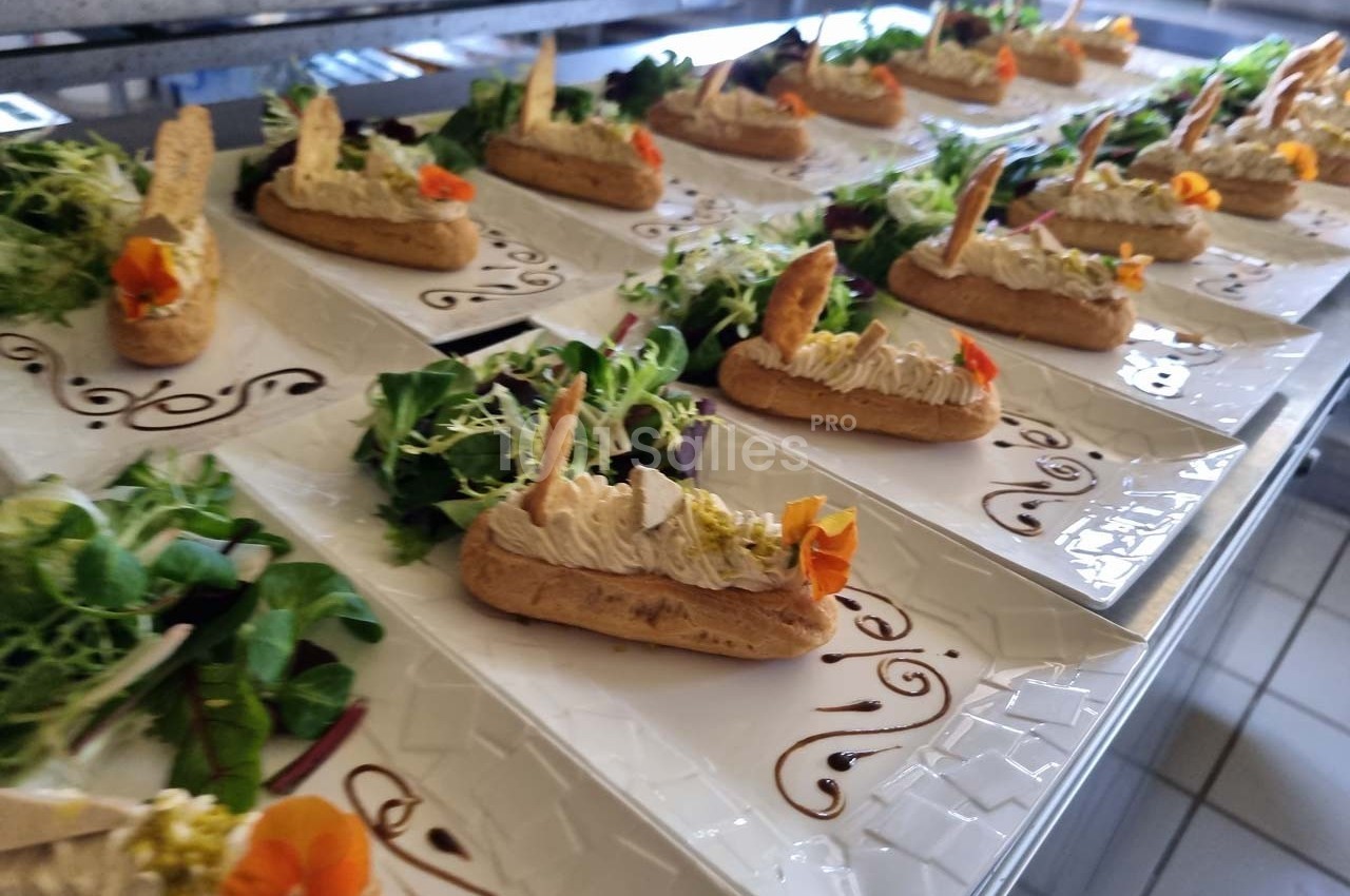Assiettes dressées avec éclairs salés garnis, décorées de fleurs comestibles et accompagnées de salade verte.