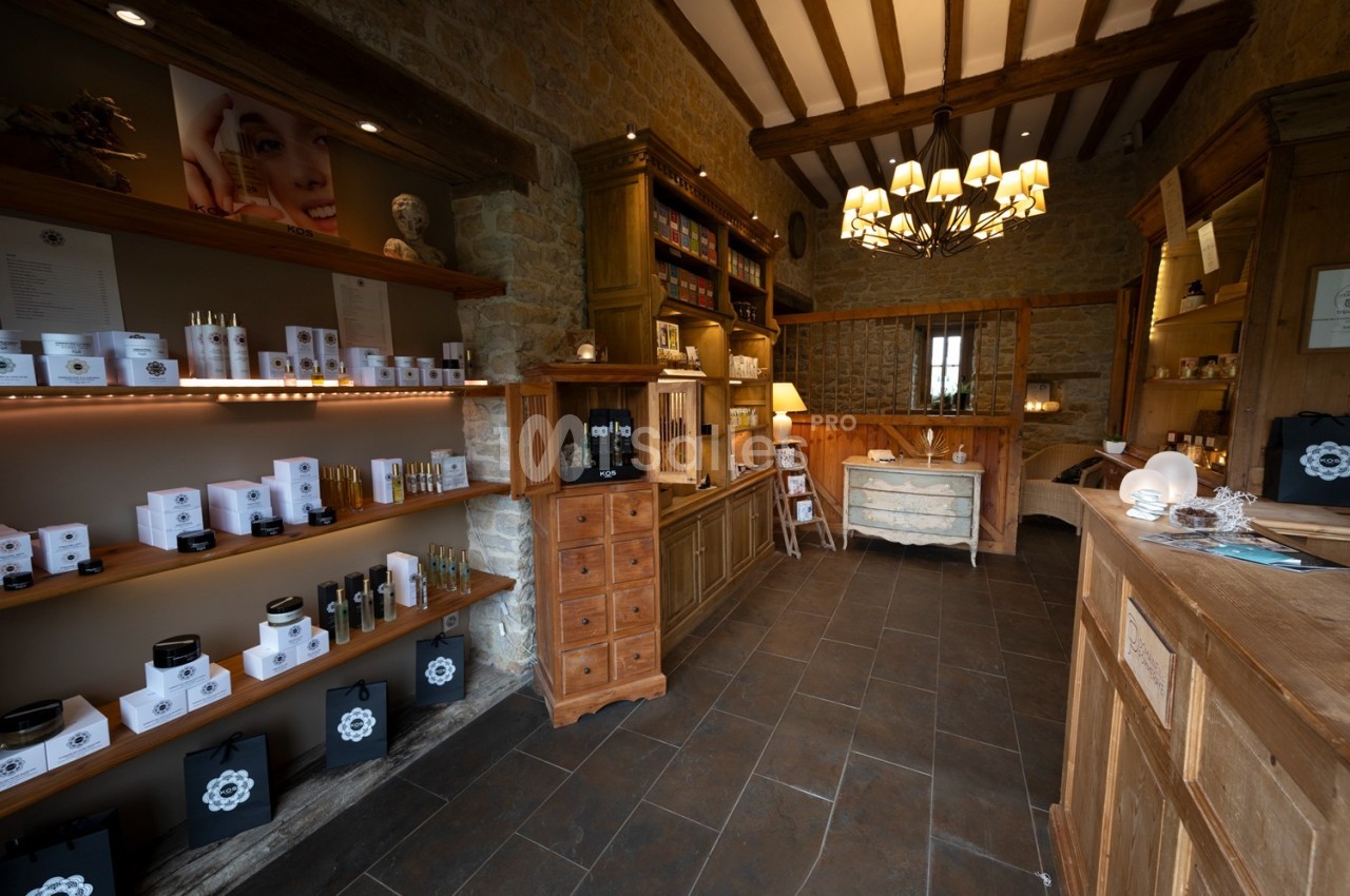 Intérieur d'une boutique avec des étagères remplies de produits de soins et un comptoir en bois dans un décor rustique.