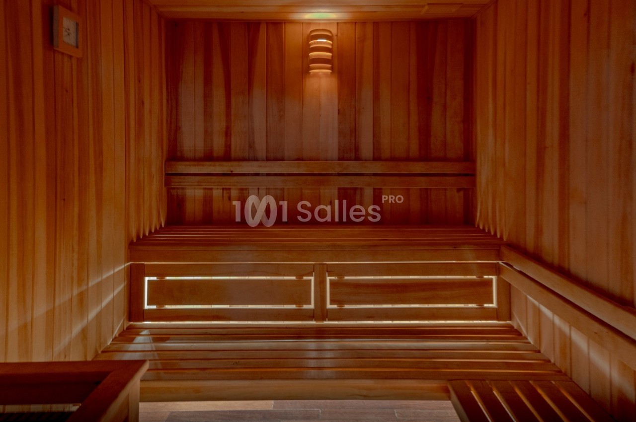 Intérieur d'un sauna en bois avec bancs superposés et éclairage tamisé.