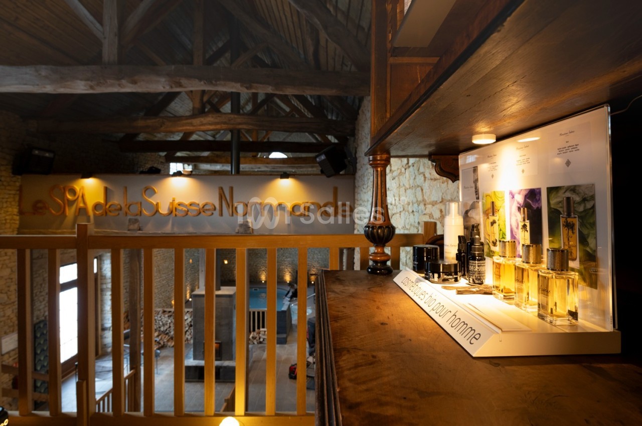 Vue intérieure d'un spa avec une étagère de produits de soin pour homme et une mezzanine en bois.
