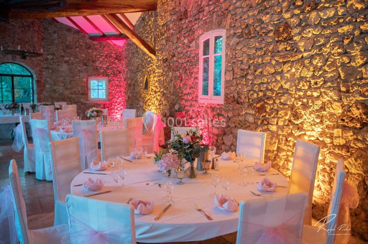 Location salle Signes (Var) - Château de Cancerilles #7 Salle de réception en pierre avec tables rondes décorées de nappes blanches, fleurs et éclairage coloré.