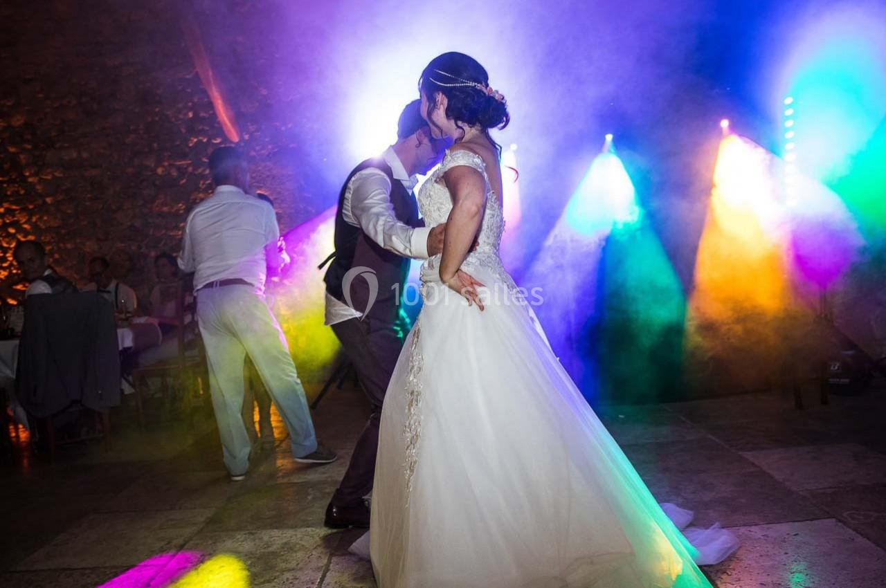 Location salle Signes (Var) - Château de Cancerilles #5 Un couple danse lors d'une soirée festive, éclairée par des lumières colorées et une ambiance animée.