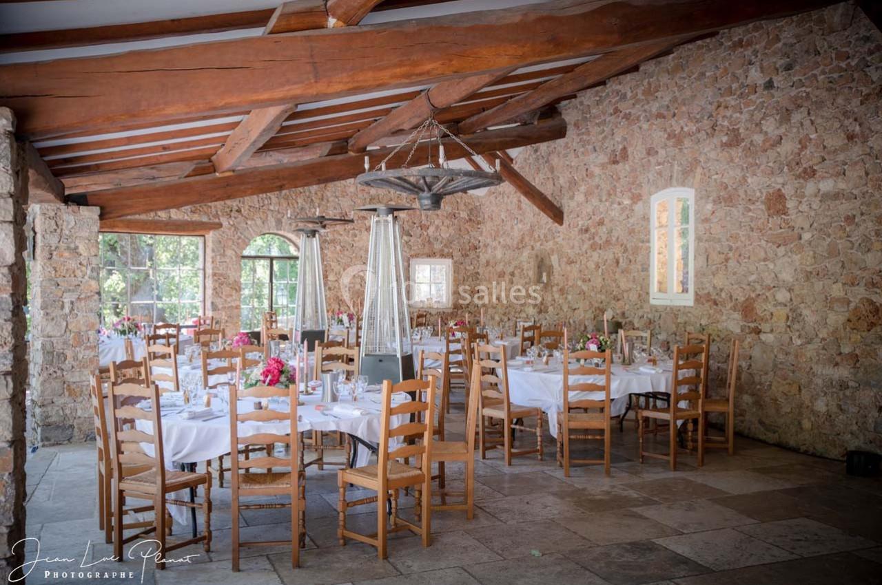 Location salle Signes (Var) - Château de Cancerilles #15 Salle de réception en pierre avec tables dressées, nappes blanches, chaises en bois et décorations florales.