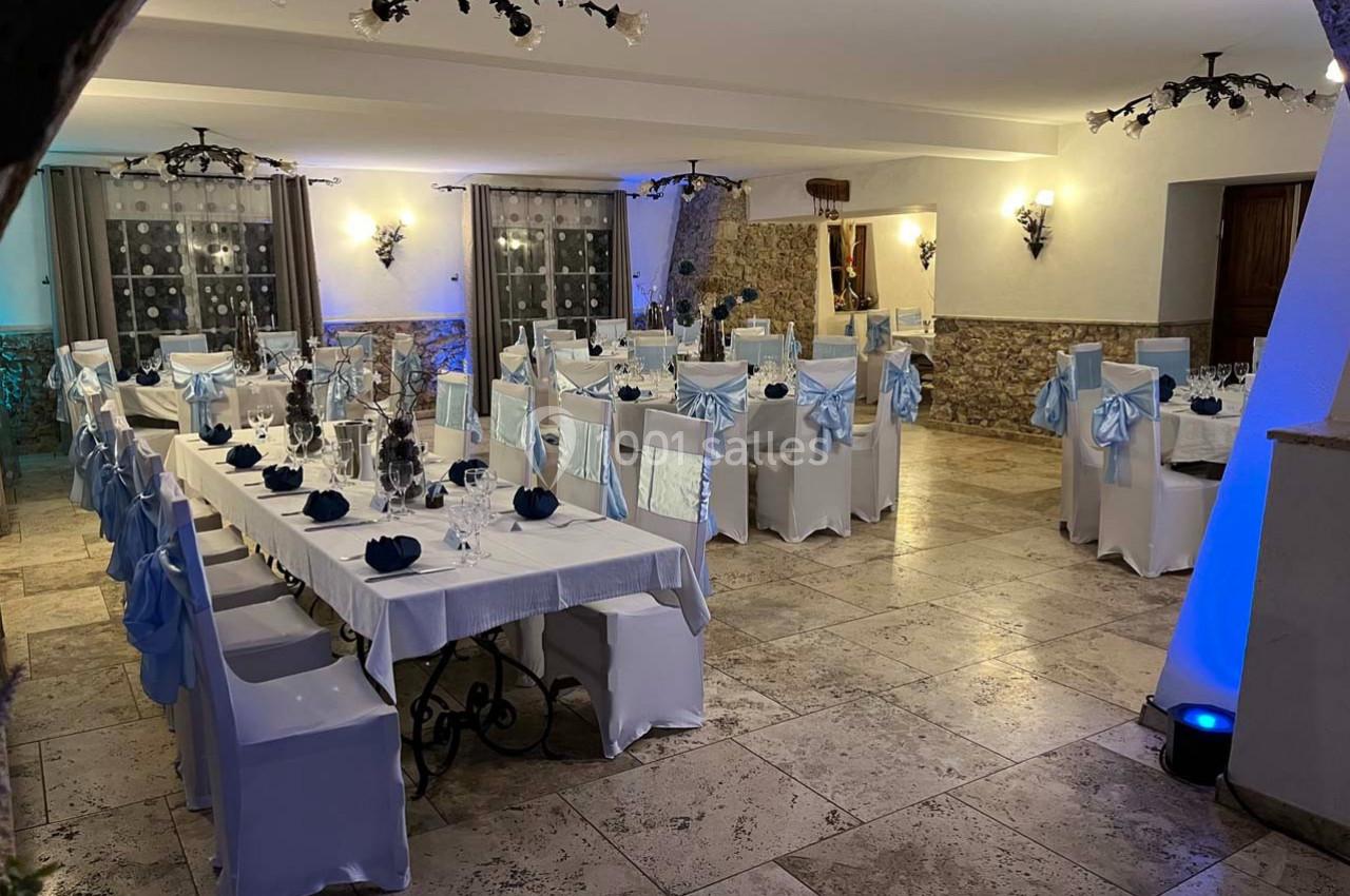 Location salle Signes (Var) - Château de Cancerilles #24 Salle de réception décorée avec des nappes blanches et des chaises ornées de nœuds bleus, éclairage chaleureux.