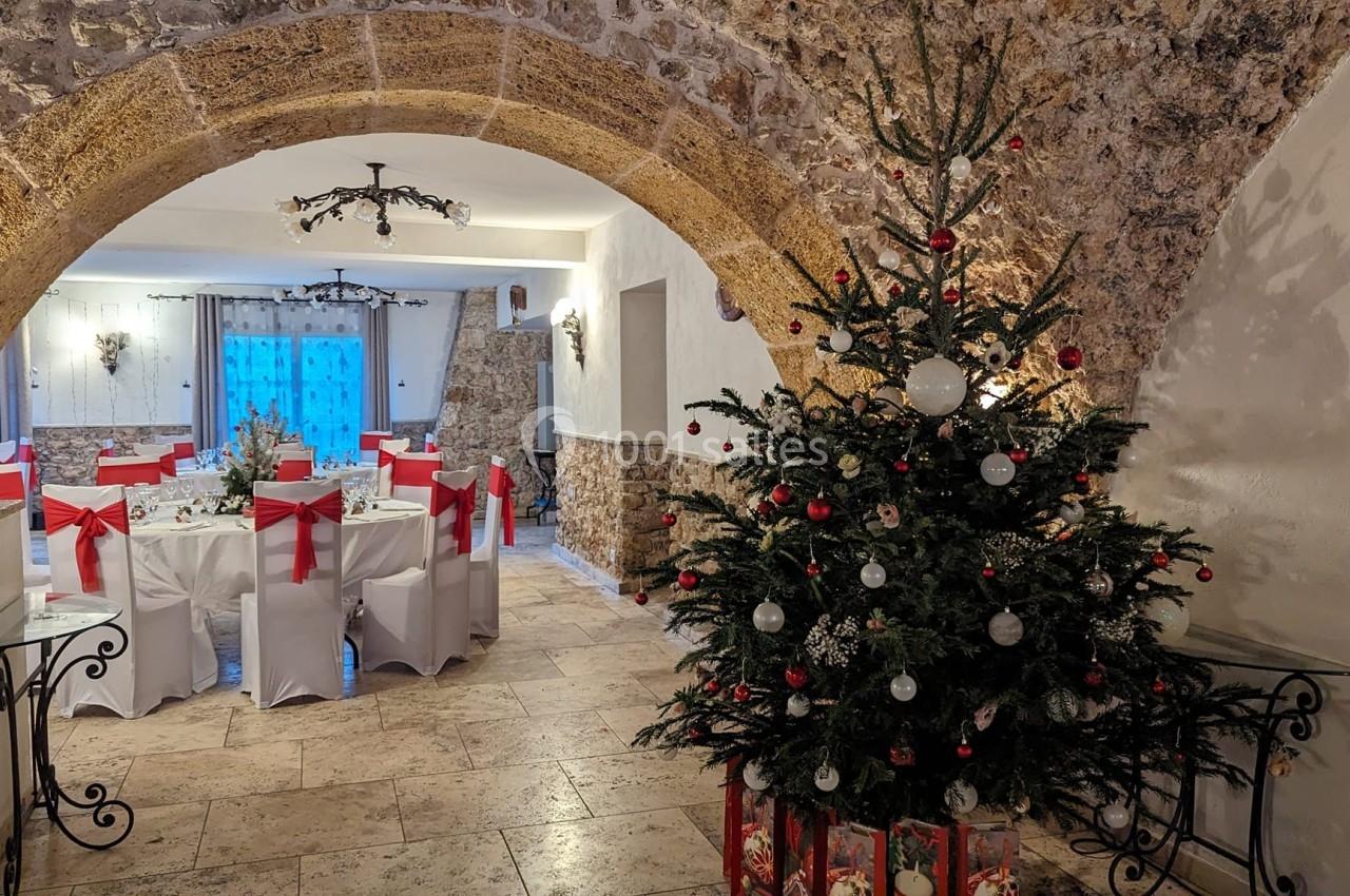Location salle Signes (Var) - Château de Cancerilles #27 Salle décorée pour une réception avec des tables ornées de nœuds rouges et un sapin de Noël illuminé au premier plan.