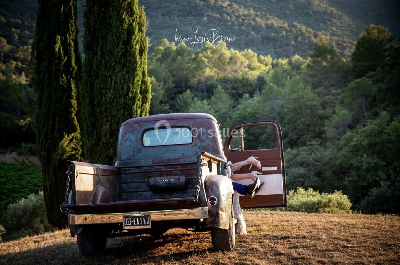 Location salle Signes (Var) - Château de Cancerilles #53 Un vieux pick-up rouillé stationné dans un paysage rural avec une personne assise sur le marchepied, porte ouverte.