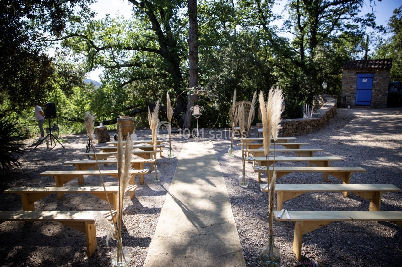 Location salle Signes (Var) - Château de Cancerilles #28 Allée centrale bordée de bancs en bois et de décorations végétales, menant à un espace de cérémonie en extérieur.