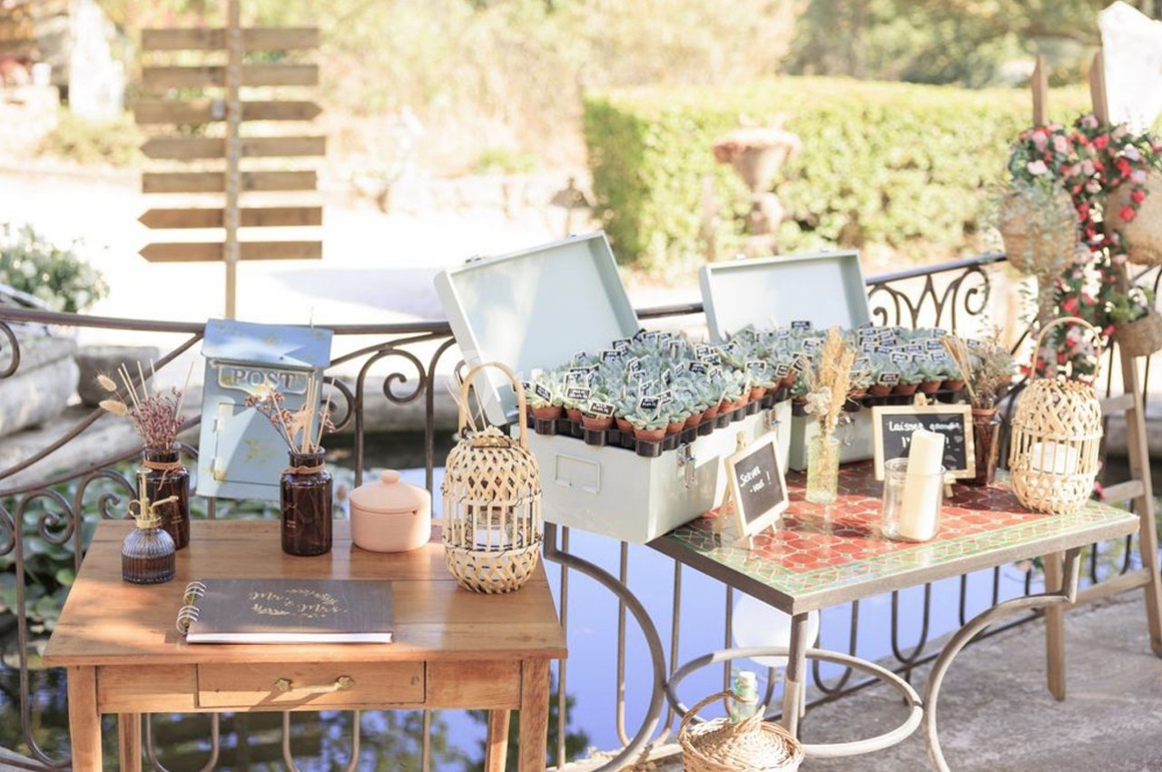 Location salle Signes (Var) - Château de Cancerilles #27 Table décorative en extérieur avec des plantes en pots, un carnet ouvert et des éléments en osier près d'un point d'eau.