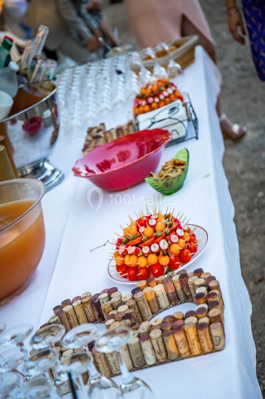 Location salle Signes (Var) - Château de Cancerilles #57 Table de buffet avec brochettes apéritives, bols de snacks, carafes de boisson et décorations en bouchons de liège.