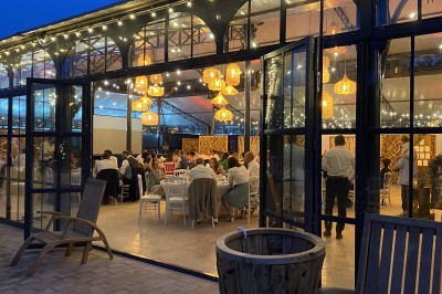 Miniature l'Orangerie de l'Orée du Bois 78 Salle de réception illuminée par des suspensions lumineuses, avec des invités assis à des tables rondes.