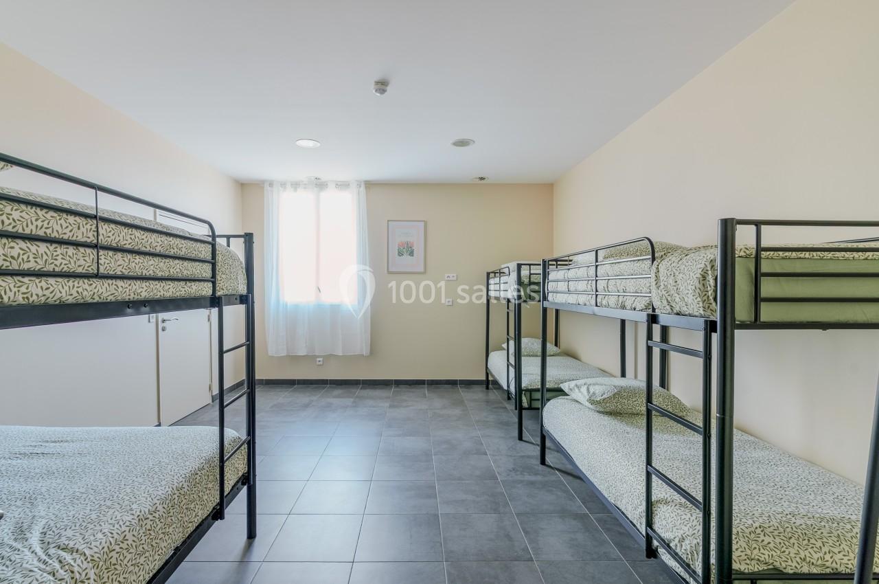 Chambre lumineuse avec quatre lits superposés, draps à motifs verts et sol en carrelage gris.