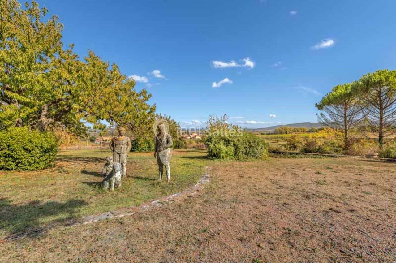 Statues représentant deux figures humaines et un chien dans un parc avec arbres et ciel dégagé en arrière-plan.