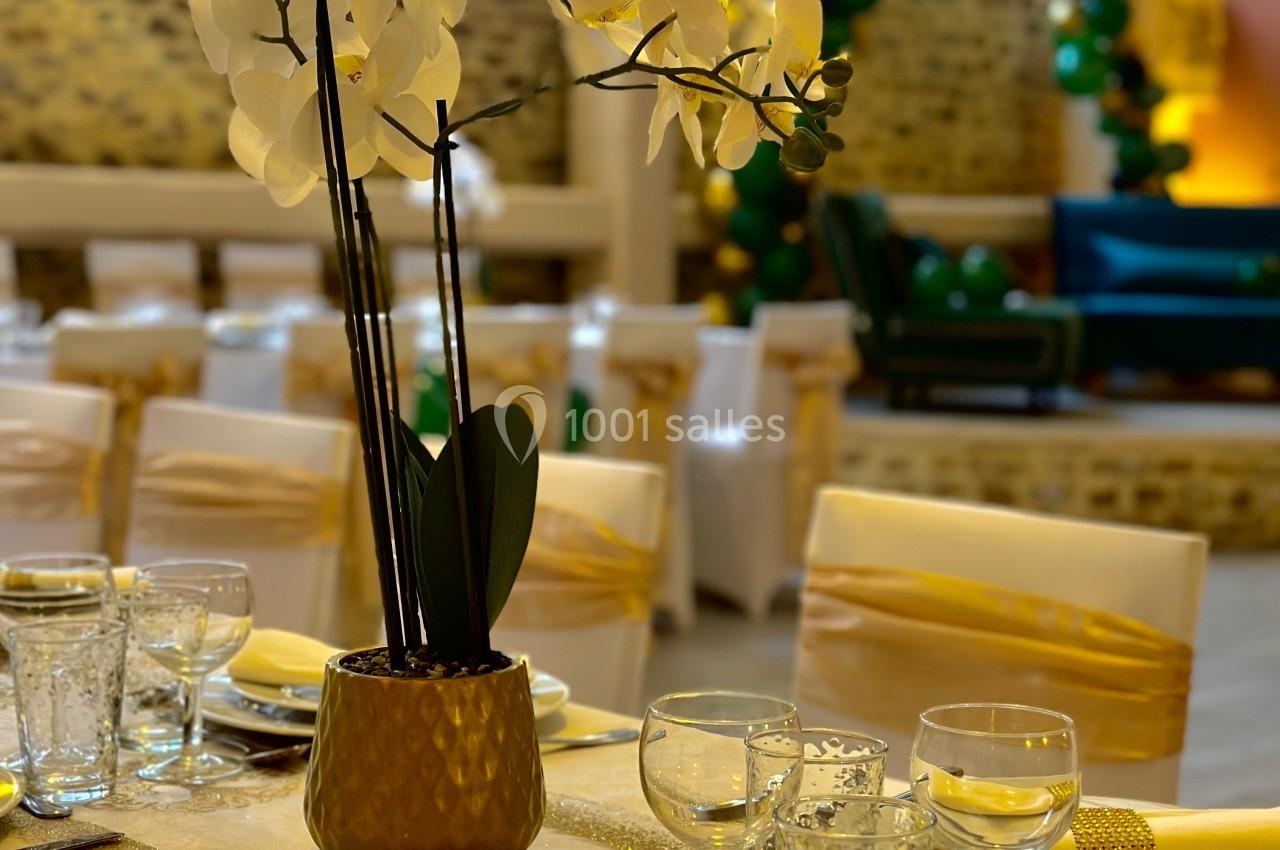 Table décorée avec élégance, ornée d'une orchidée blanche et de vaisselle raffinée dans une salle de réception lumineuse.