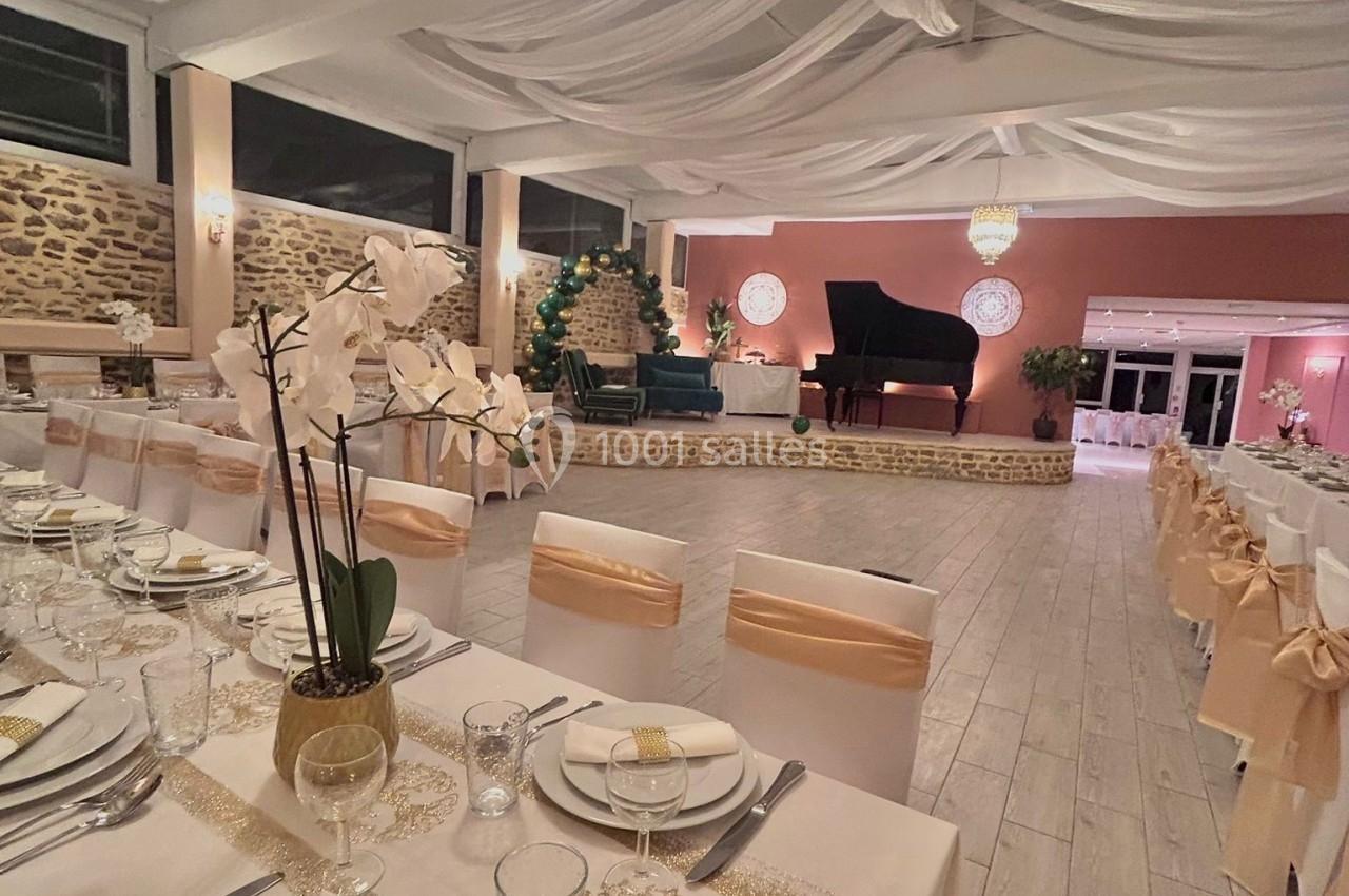 Salle de réception élégante avec tables dressées, orchidées en centre de table et scène avec piano à queue.